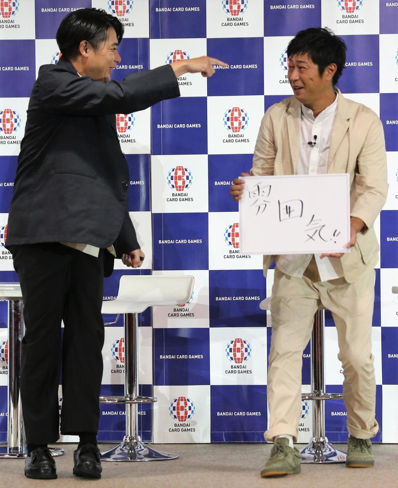「ドラゴンボール　スーパーカードゲーム発表会」でフリップを見せる尾形貴弘、左は吉村崇、尾形貴弘