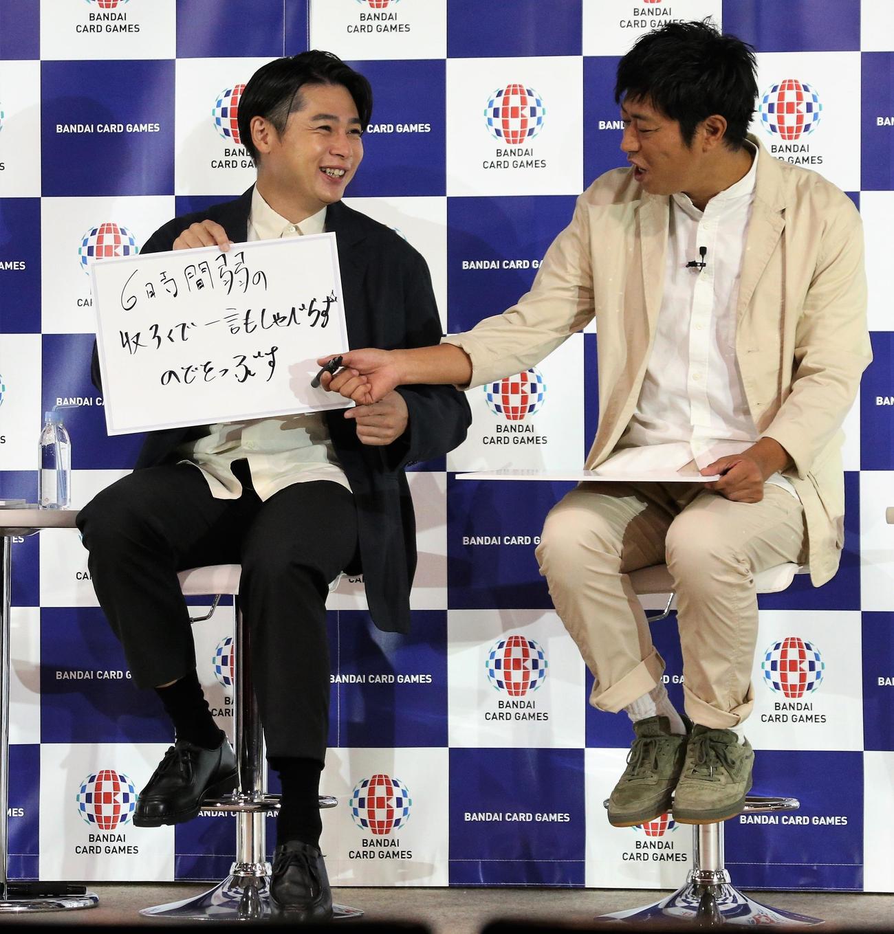 「ドラゴンボール　スーパーカードゲーム発表会」でフリップを見せる吉村崇と尾形貴弘