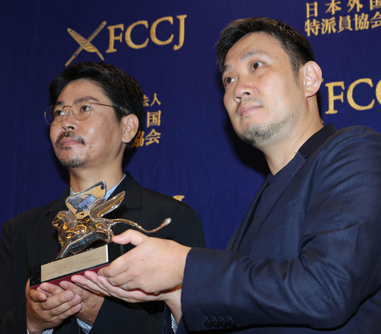 「悪は存在しない」ベネチア国際映画祭報告記者会見で、銀獅子賞のトロフィーを手に写真に納まる濱口竜介監督（右）と主演を務めた大美賀均（撮影・河田真司）