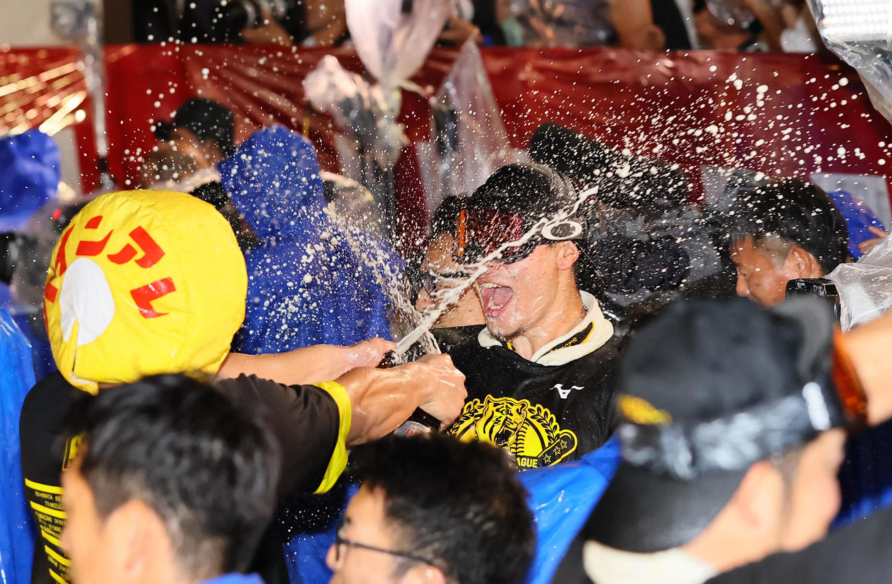 祝勝会でパインアレのかぶり物をかぶった選手からビールを掛けられる佐藤輝（撮影・上田博志）