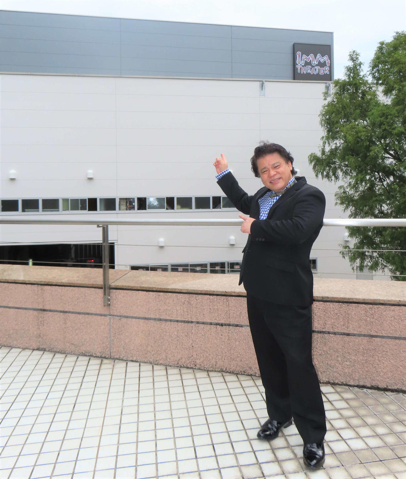 建設中の新劇場「IMM THEATER」を指さすジミー大西
