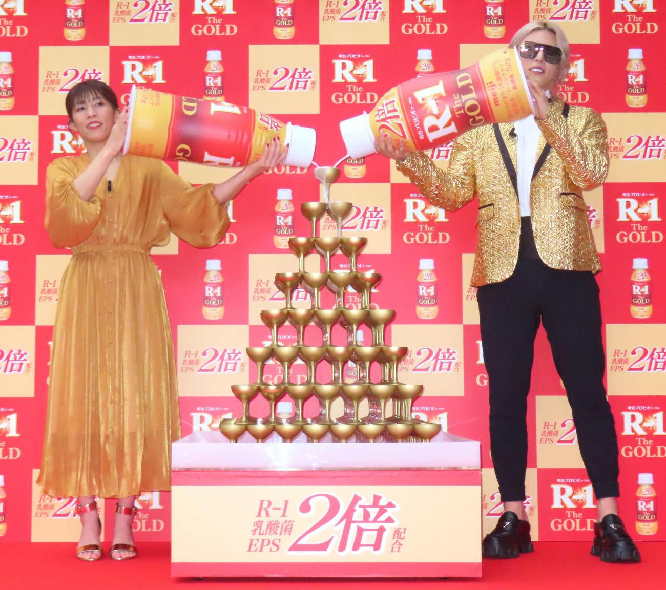 シャンパンタワーを模した「R－1 The GOLDタワー」にR－1を注ぎ込む吉田沙保里さん（左）とローランド