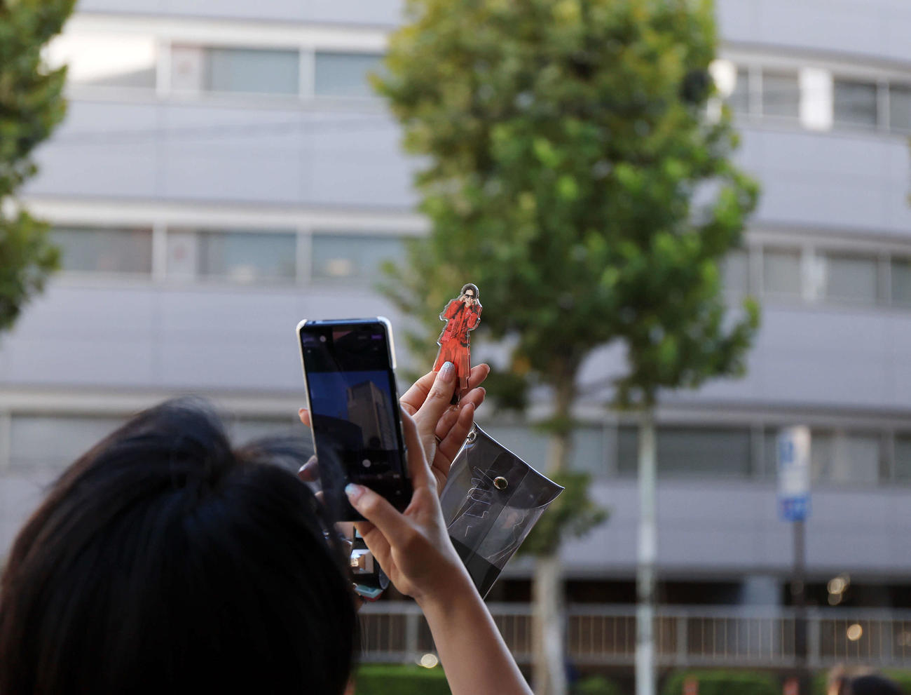 社名ロゴが撤去されたジャニーズ事務所本社ビルの前で、タレントのグッズを手にスマホで撮影しているファンの姿も（撮影・浅見桂子）