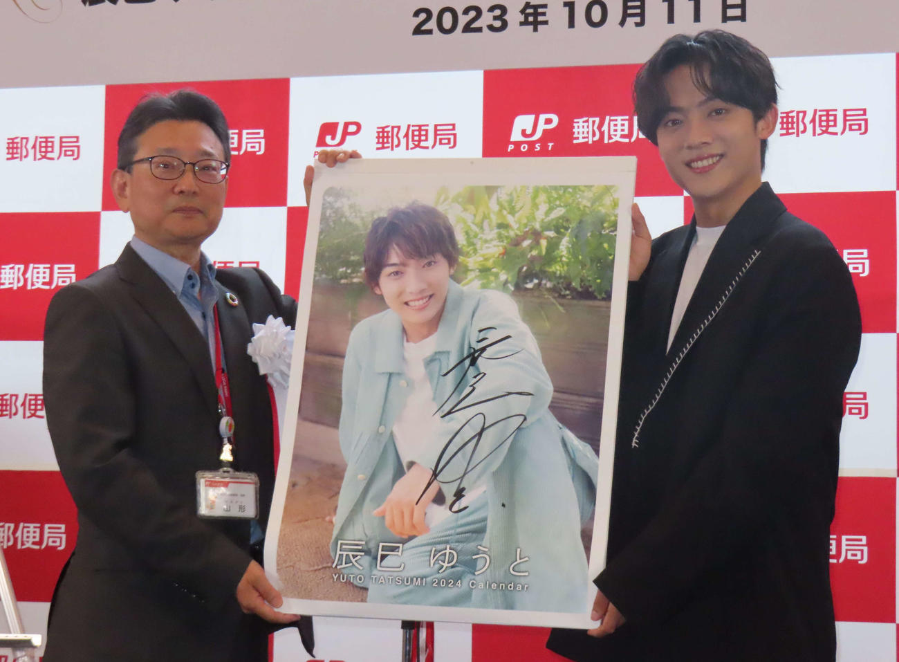 東京中央郵便局の山形局長（左）にカレンダーを贈呈する辰巳ゆうと