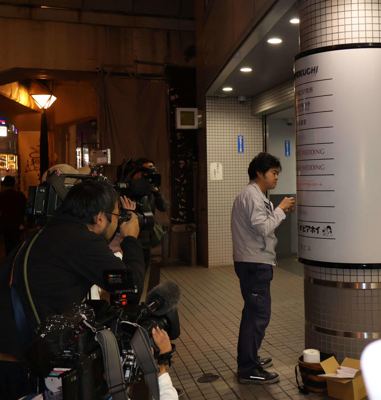 店名を記した案内文字を消す作業をするスタッフ（撮影・村上久美子）