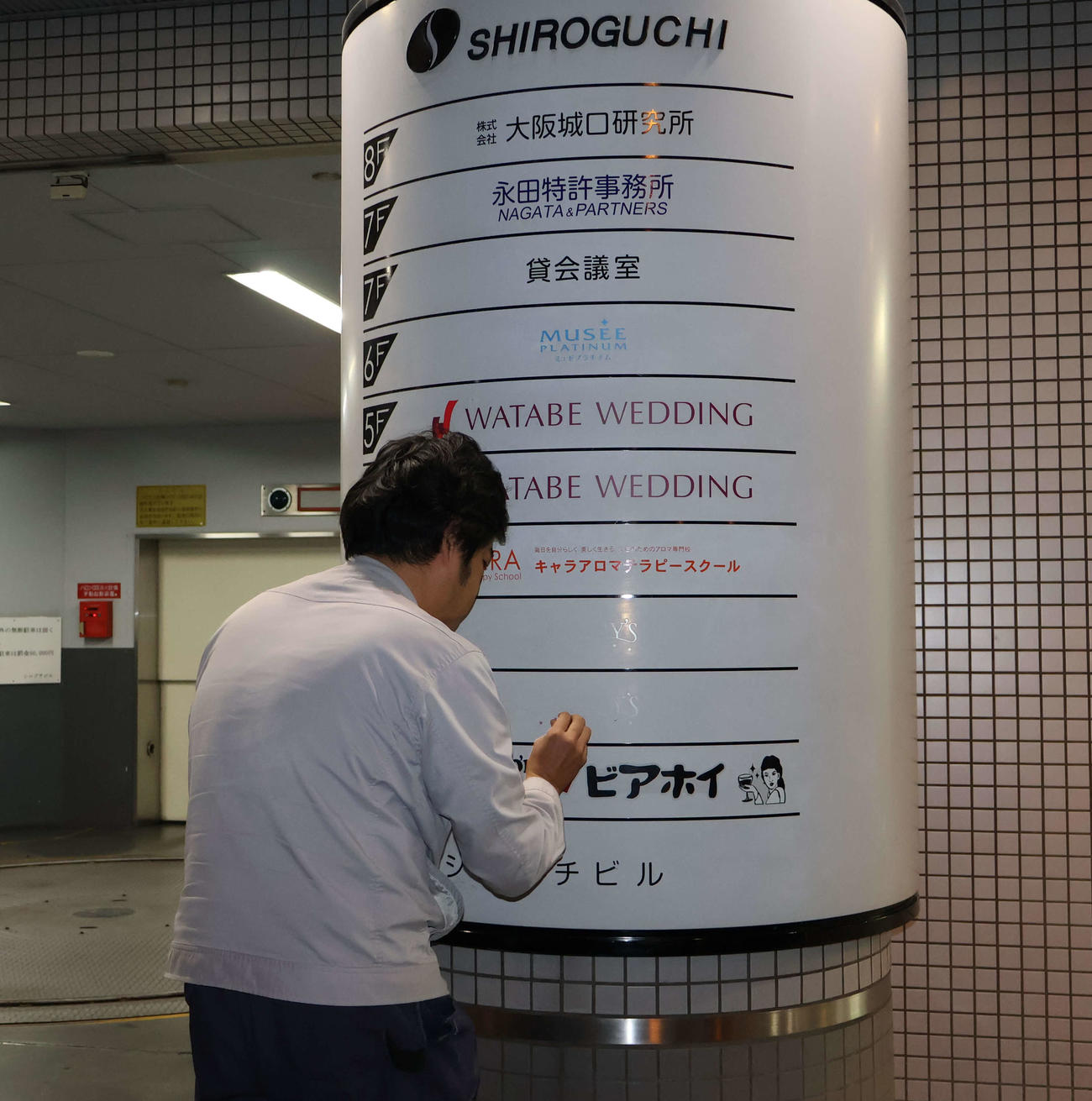店名を記した案内文字を消す作業をするスタッフ（撮影・村上久美子）