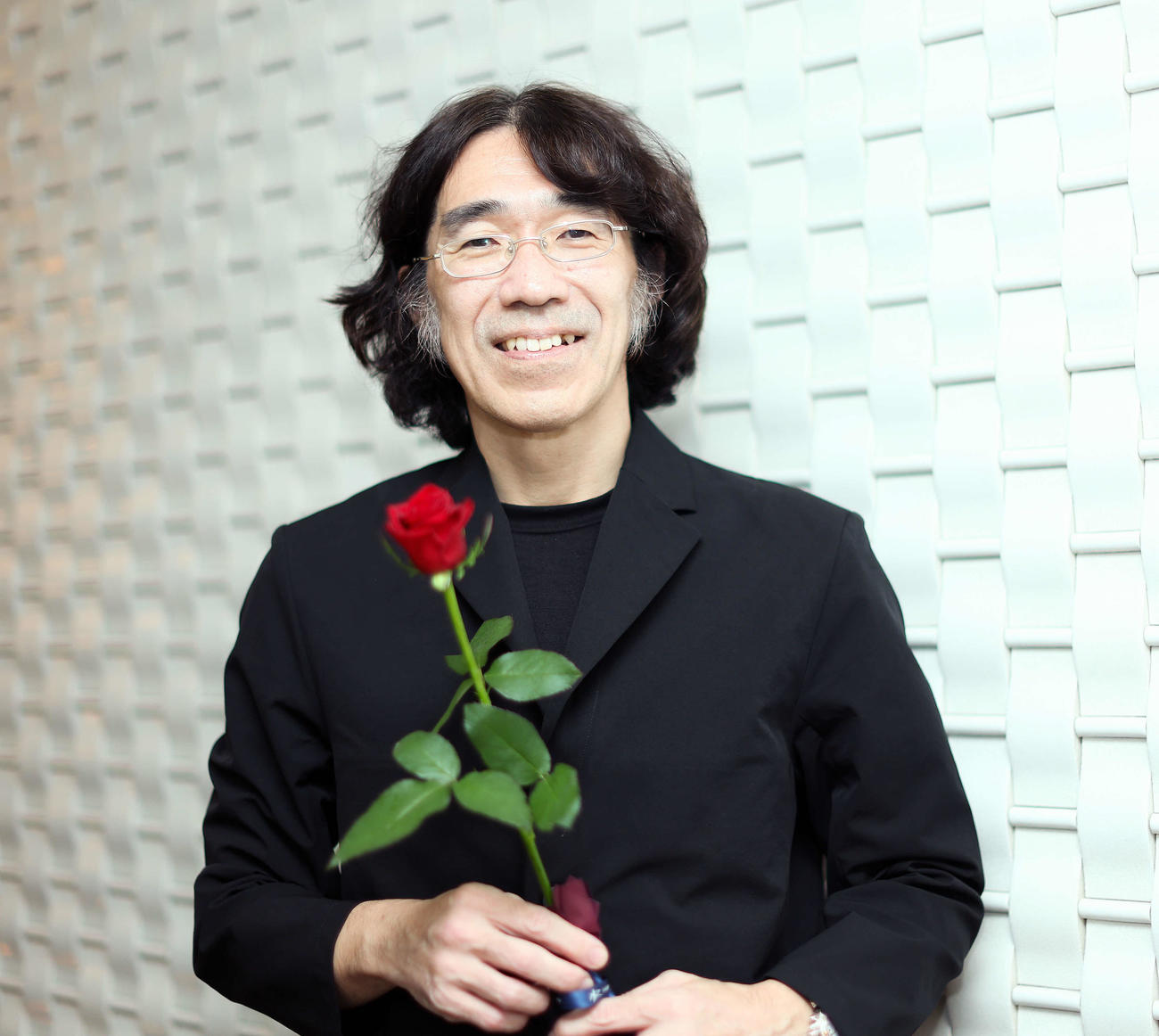 映画「くるりのえいが」完成披露上映会舞台あいさつを終え、バラの花を手に写真に納まる佐渡岳利監督（撮影・河田真司）