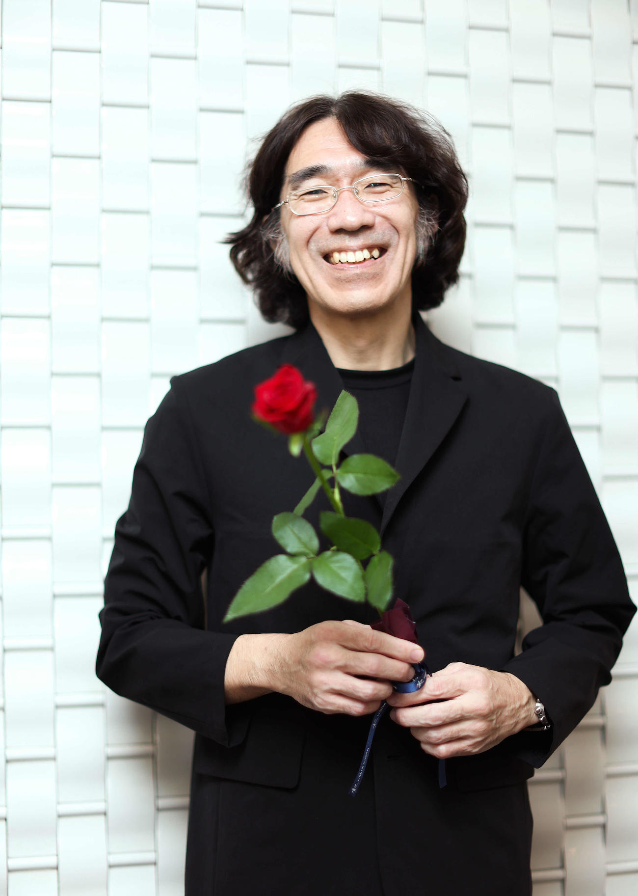 映画「くるりのえいが」完成披露上映会舞台あいさつを終え、バラの花を手に写真に納まる佐渡岳利監督（撮影・河田真司）