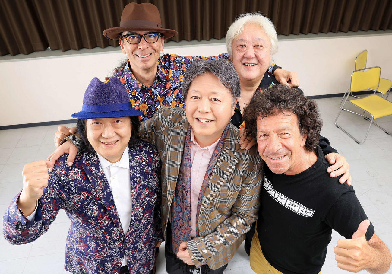 笑顔で元気いっぱいにポーズをとるゴダイゴの、前列左からミッキー吉野、タケカワユキヒデ、トミー・スナイダー、後列左からスティーブ・フォックス、吉澤洋治（撮影・浅見桂子）