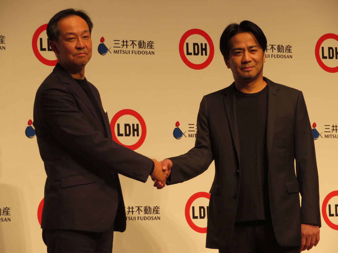 株式会社LDH JAPANと三井不動産株式会社による記者発表会に出席し、握手を交わす三井不動産の若林瑞穂氏とEXILEのHIRO