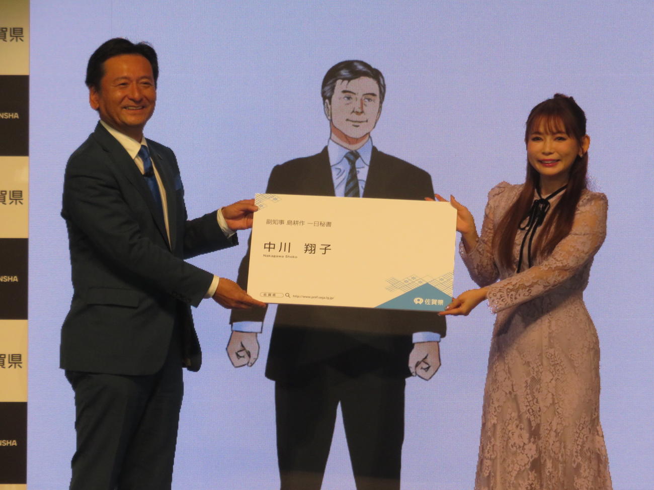 山口祥義知事から「1日秘書」の名刺を渡される中川翔子（右）中央は島耕作（C）弘兼憲史／講談社
