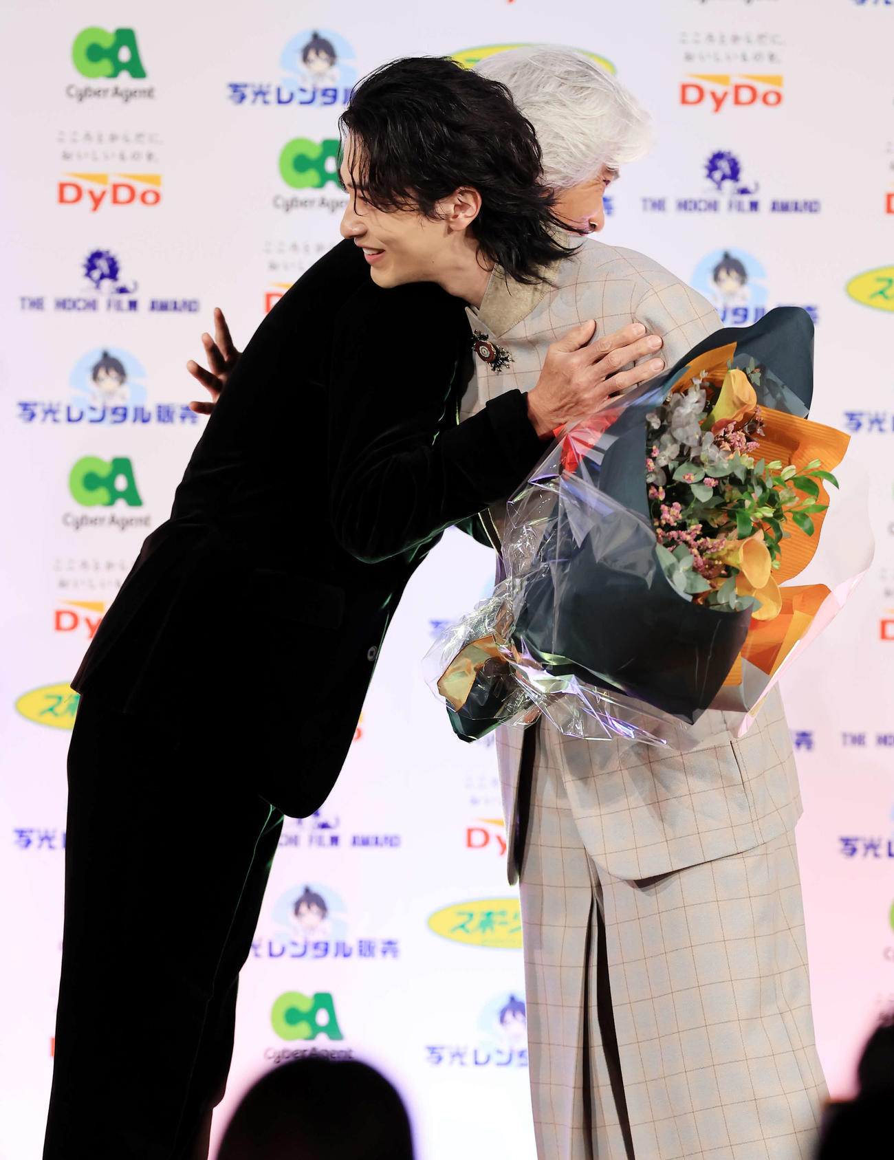 報知映画賞主演男優賞の横浜流星（右）は、サプライズ登壇の佐藤浩市から花束を贈られ抱擁する（撮影・浅見桂子）