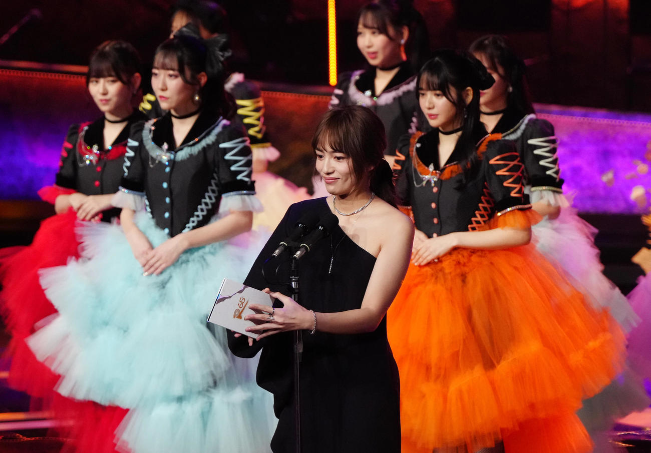 最優秀新人賞の発表を行う司会の川口春奈（手前）。後方は発表を待つFRUITS ZIPPERのメンバーたち（撮影・江口和貴）