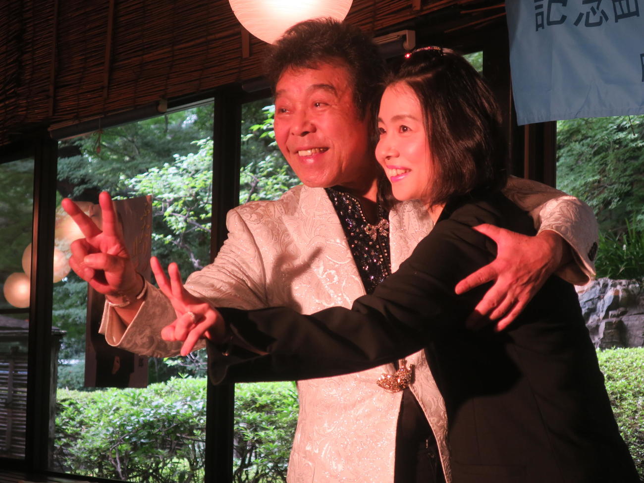 「ふたりの止まり木」にちなんで指を「2」を表現する冠二郎（左）とみなこ夫人（2017年8月撮影）