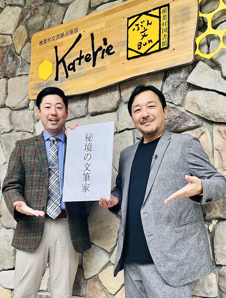 「秘境の文筆家」のキャッチフレーズを手にする椎葉村役場地域振興課・小宮山剛氏（左）と今村翔吾氏