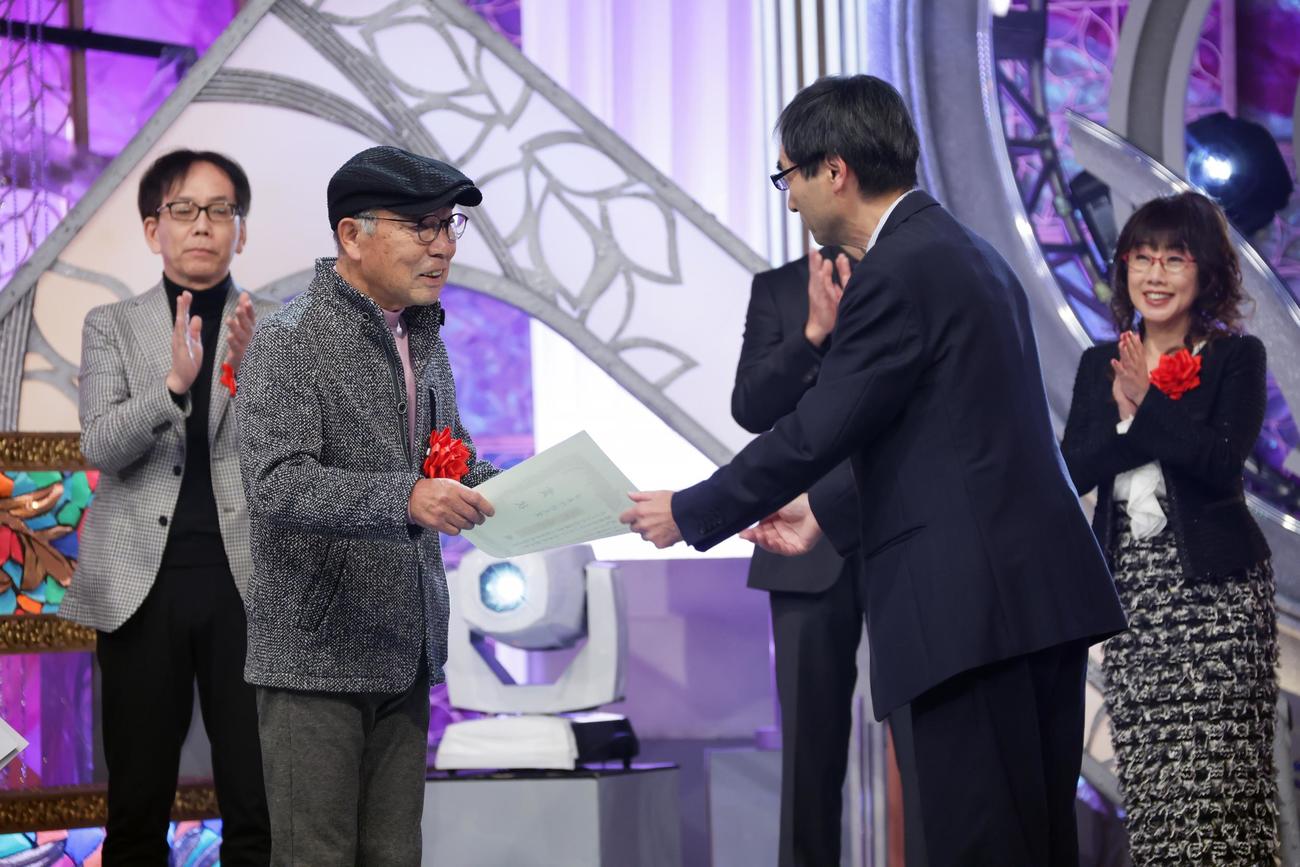 審査委員長の富澤一誠氏（手前右）から表彰状を受け取る、いではく氏(C)BSテレ東