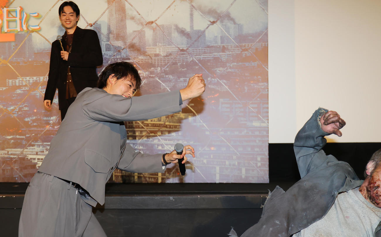劇場版「君と世界が終わる日に」公開記念舞台あいさつで、ゴーレムを退治する竹内涼真。後方は菅田将暉（撮影・野上伸悟）
