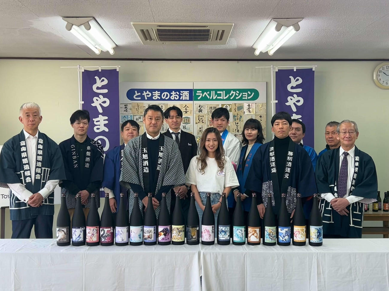 伊東楓さん（前列中央）がデザインした「復興2024ボトル」。富山県酒造組合のメンバーと