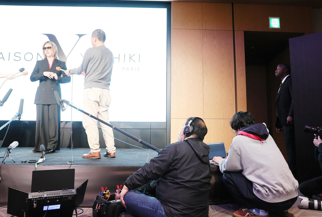 外国人SP（右端）が見つめる中、囲み取材に応じるYOSHIKI（撮影・足立雅史）