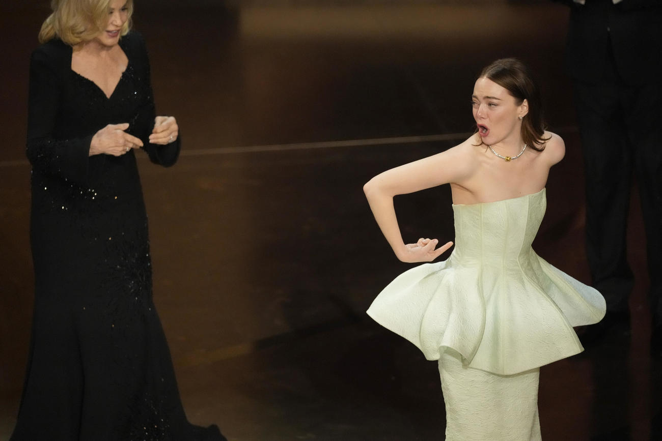第96回アカデミー賞授賞式で、主演女優賞を受賞したエマ・ストーン（右）はドレスのファスナーが壊れてしまい困惑の表情。左はジェシカ・ラング（AP）