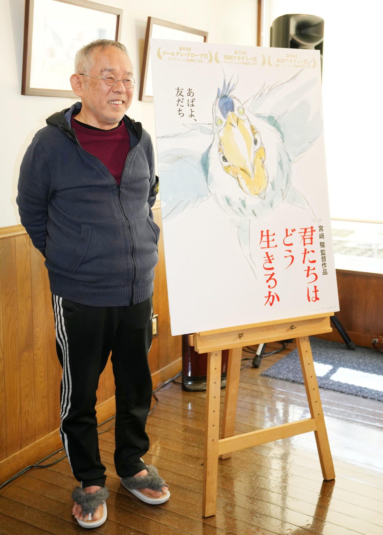 「君たちはどう生きるか」のポスターを横に笑顔をみせる鈴木敏夫プロデューサー（撮影・横山健太）