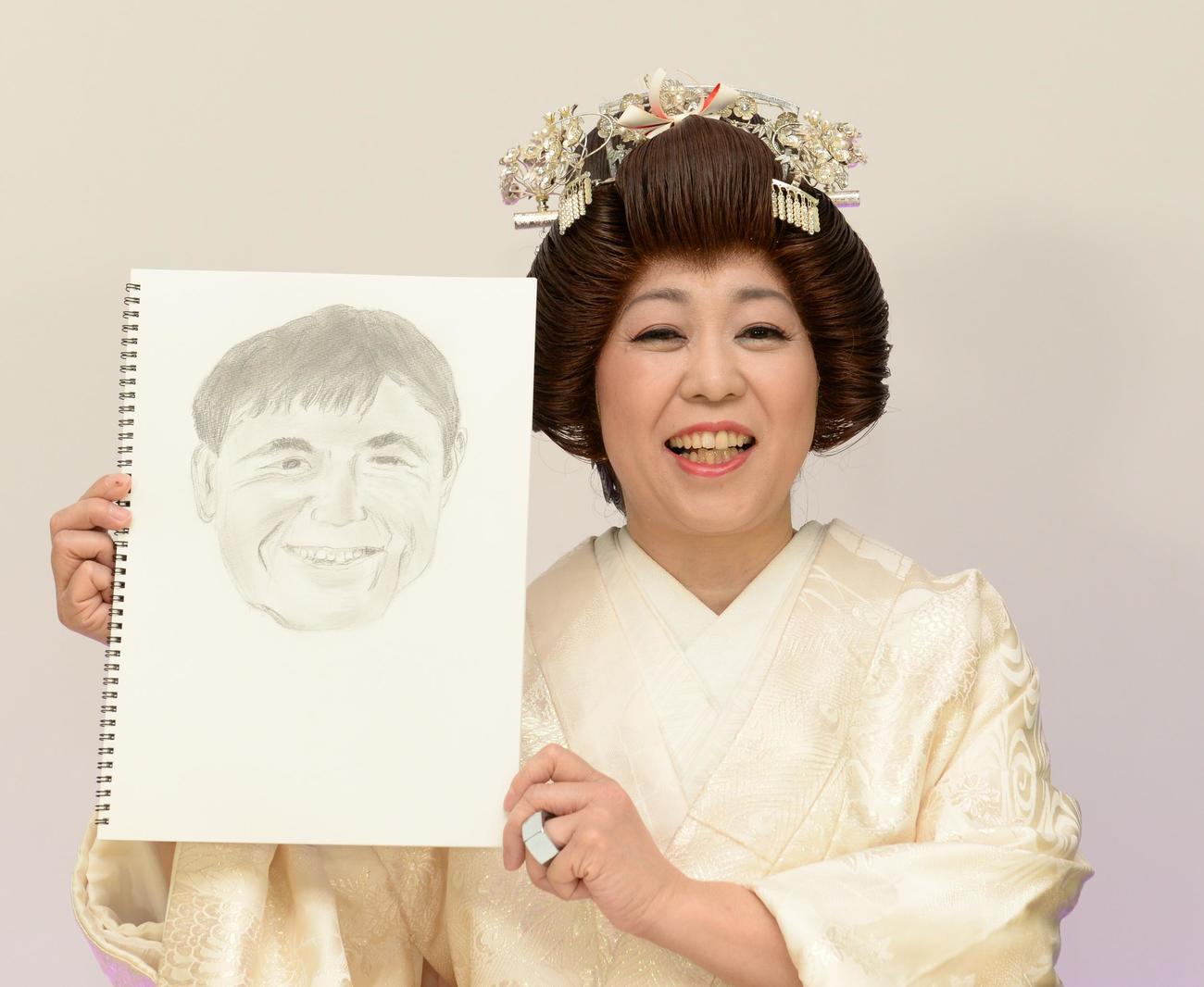 結婚相手の似顔絵を手にして結婚報告をする八幡カオル