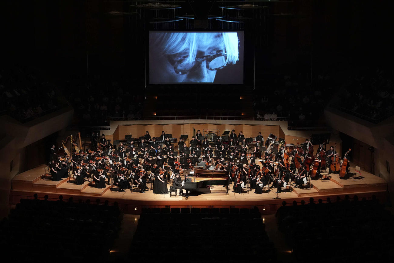 スクリーンに生前の坂本龍一さんの姿が映し出される中、演奏が行われた「坂本龍一監督追悼　東北ユースオーケストラ演奏会　2024」