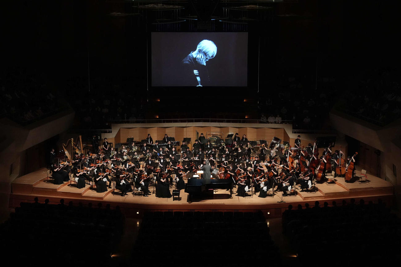 スクリーンに生前の坂本龍一さんの姿が映し出される中、演奏が行われた「坂本龍一監督追悼　東北ユースオーケストラ演奏会　2024」