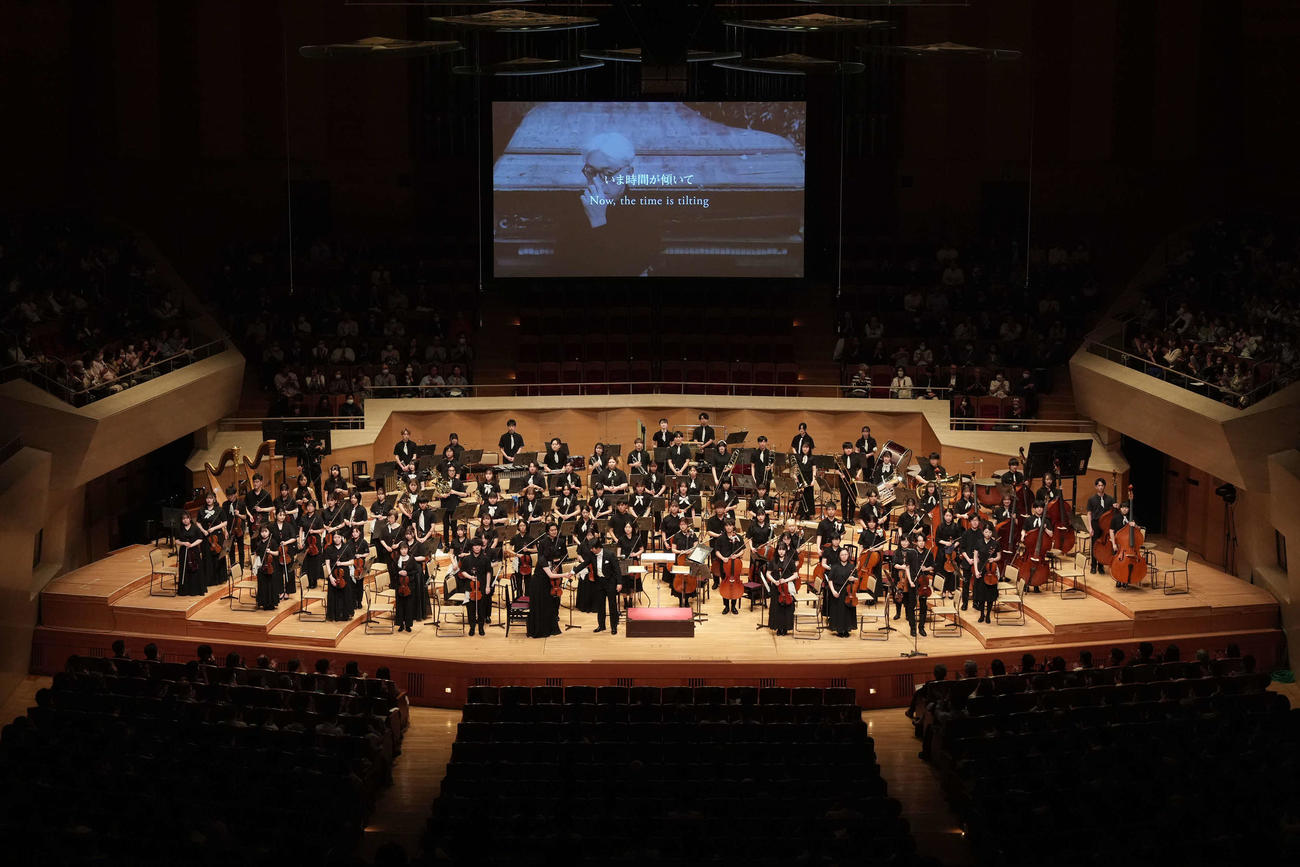 スクリーンに生前の坂本龍一さんの姿が映し出される中、演奏が行われた「坂本龍一監督追悼　東北ユースオーケストラ演奏会　2024」