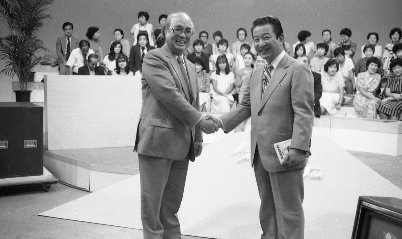 ベストセラー「気くばりのすすめ」の著者、NHK鈴木健二アナウンサー（左）が、フジテレビの番組にゲスト出演となったが、NHK上層部からブラウン管登場は許可されず、カメラに背を向け声だけの出演となった。右はこの番組の司会者でNHK時代の先輩アナウンサー小川宏（1983年8月31日）
