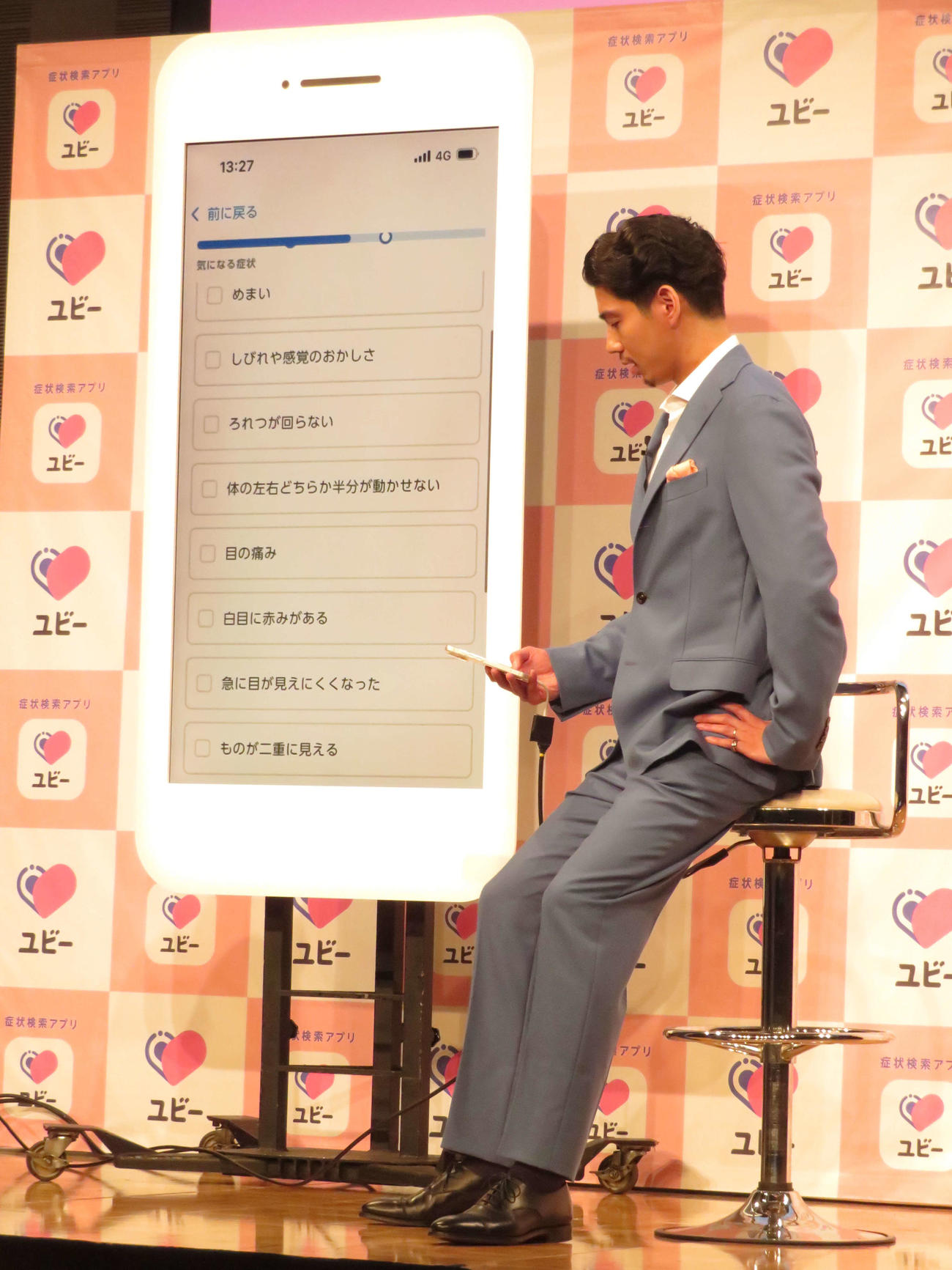 「ユビー」の新TVCM発表会・事業説明会に出席し、アプリを実際に使用する賀来賢人