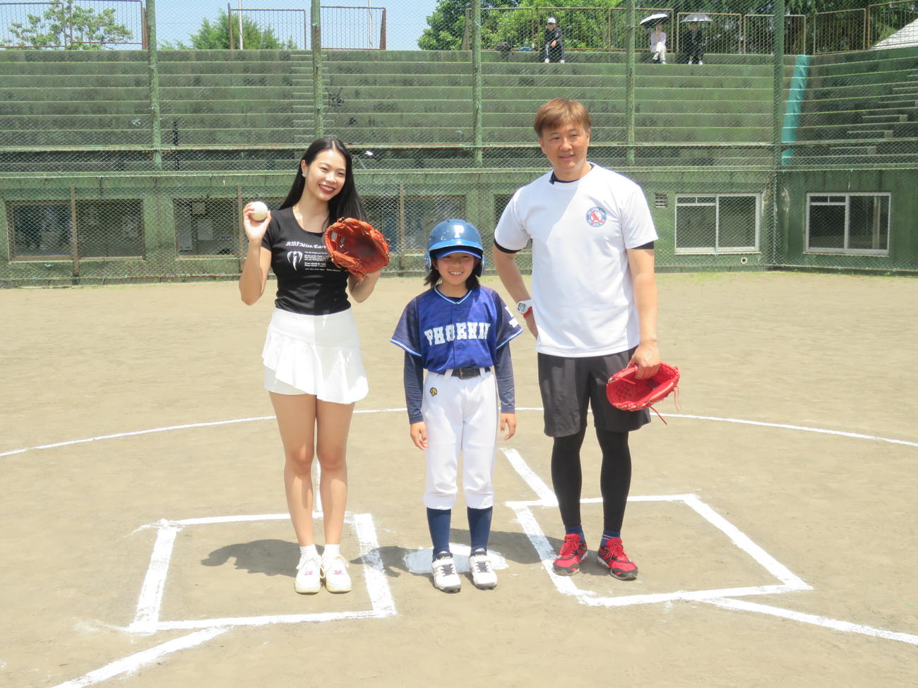 「十日町・津南　少年野球教室」の始球式で、左から投手の小久保春菜、打者の関沢菜那さん（芦ケ崎小４年）、捕手の岡島秀樹氏