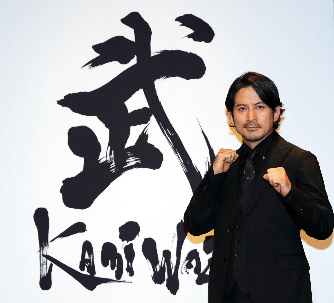 「武」の文字を背にポーズを決める岡田准一（撮影・たえ見朱実）