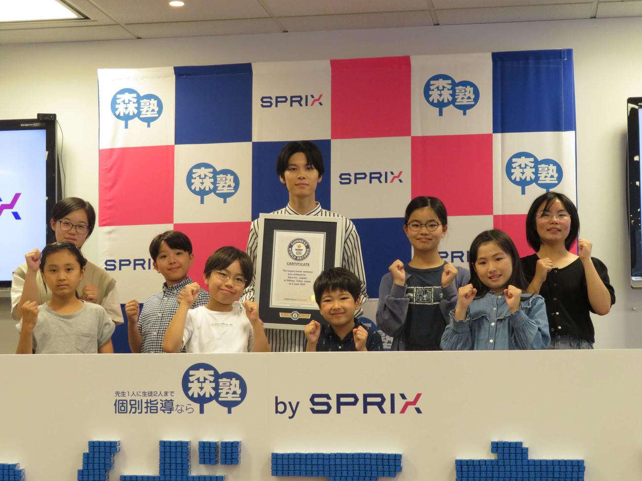 「消しゴムでギネス世界記録〓（商標記号）に挑戦！～これからの未来を担う子どもたちへ贈る巨大消しゴムエール～」でギネス認定書を受け取った萩原利久と参加者の子どもたち