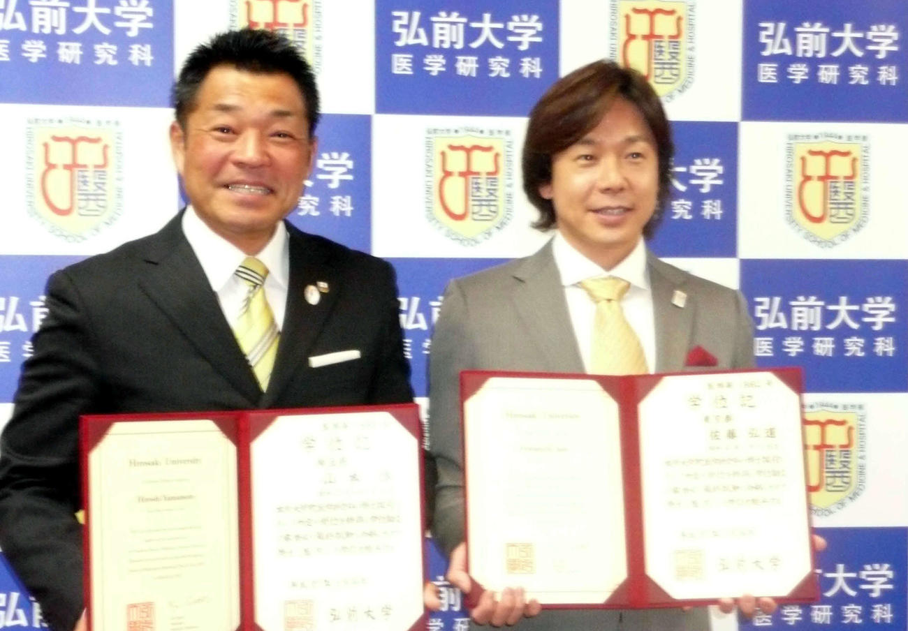 弘前大大学院の博士学位記授与式に出席したアーチェリー五輪銀メダリストの山本博（左）とタレントの佐藤弘道＝2015年3月24日