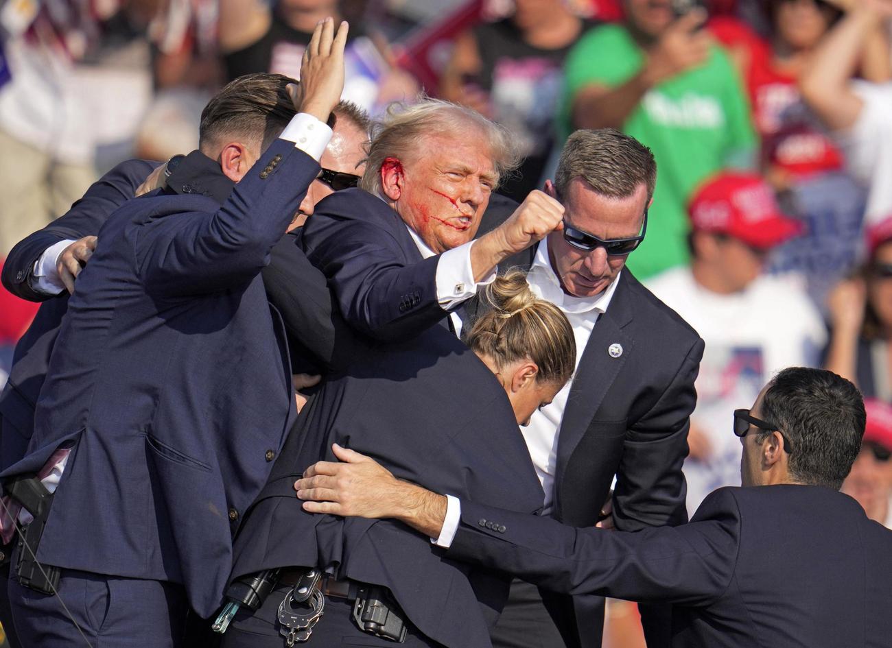 選挙集会の演説中に銃撃され、拳を上げながら降壇するトランプ前米大統領＝13日、米ペンシルベニア州バトラー（AP＝共同）