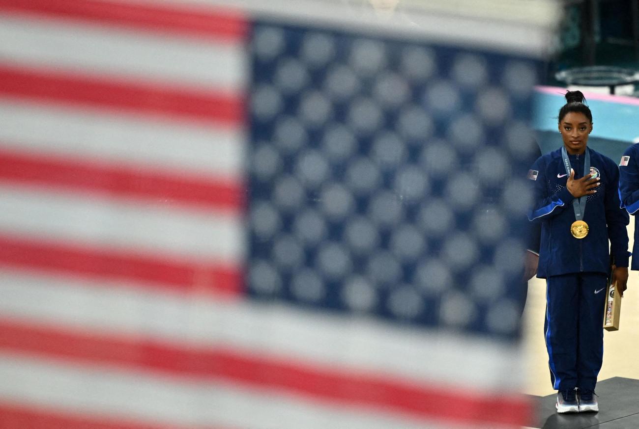 体操女子団体総合で金メダルを獲得し、国歌が流れる中、星条旗を見つめる米シモーネ・バイルズ（ロイター）