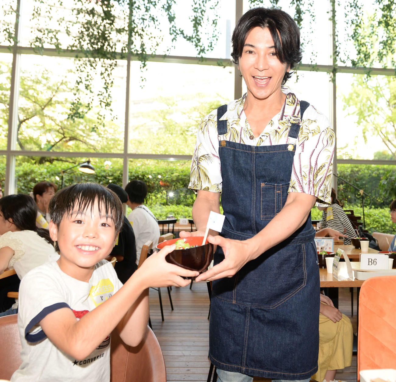 テレビ朝日の「サマステスペシャルコラボカフェ」で、千葉県から来た小4の村上悠輝さんに焼き鳥丼を手渡す武田真治
