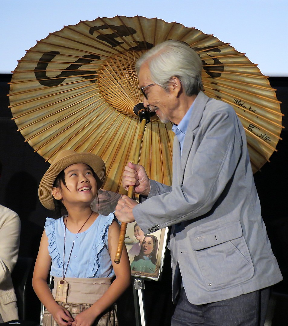 「男はつらいよ　55周年記念ファン大感謝祭」で、抽選に当たった8歳のファンに「とらや」の番傘をプレゼントする山田洋次監督（右）
