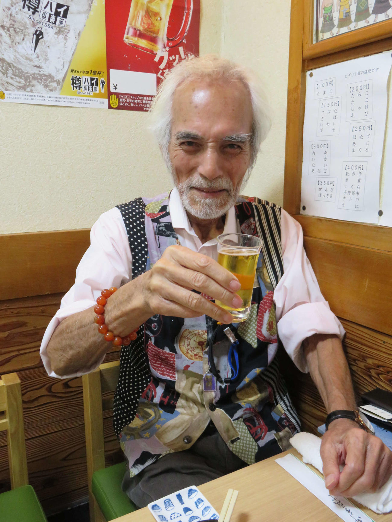 インタビューの合間に笑顔でビールのグラスを傾ける堀田眞三