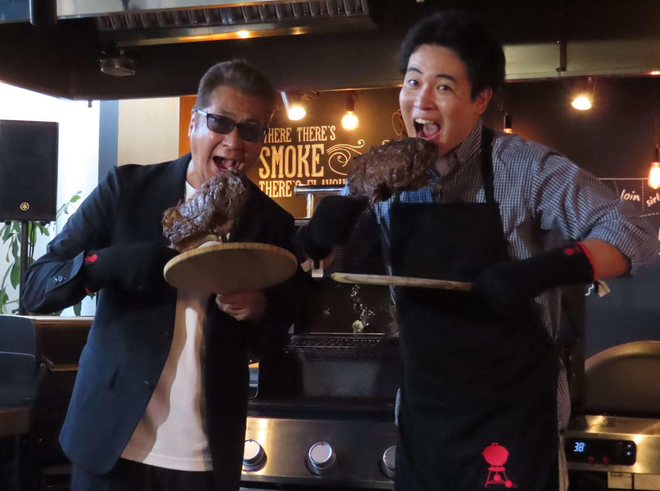 木村徹二のワンマンコンサート成功祈念イベントで、大きな肉に笑顔を見せる山川豊（左）と木村徹二（撮影・野見山拓樹）