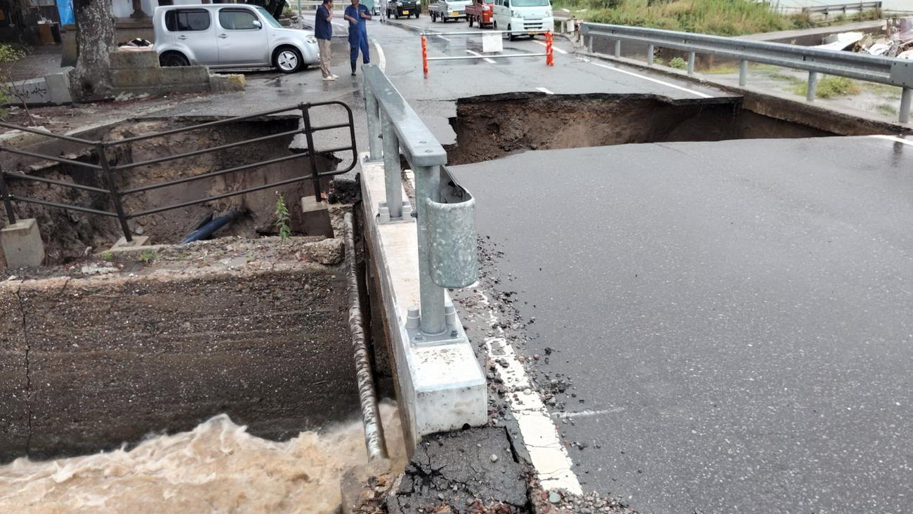 大雨の影響で大きく陥没した石川・珠洲市の道路や歩道。小川は濁流に（出村正幸さん提供）