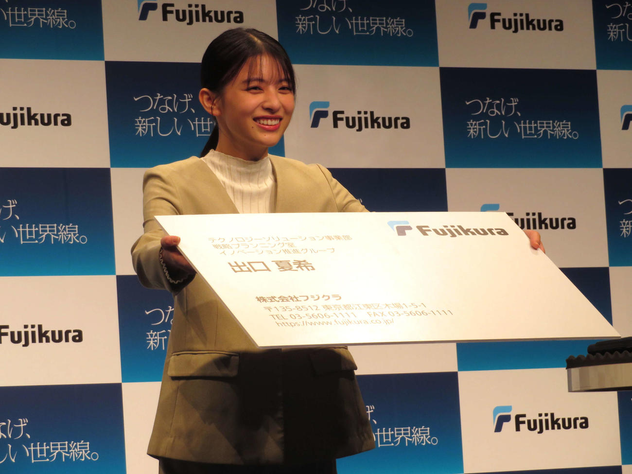 「つなげ、新しい世界線。フジクラ新CM発表会」に出席し、特大の名刺を使ってあいさつする出口夏希