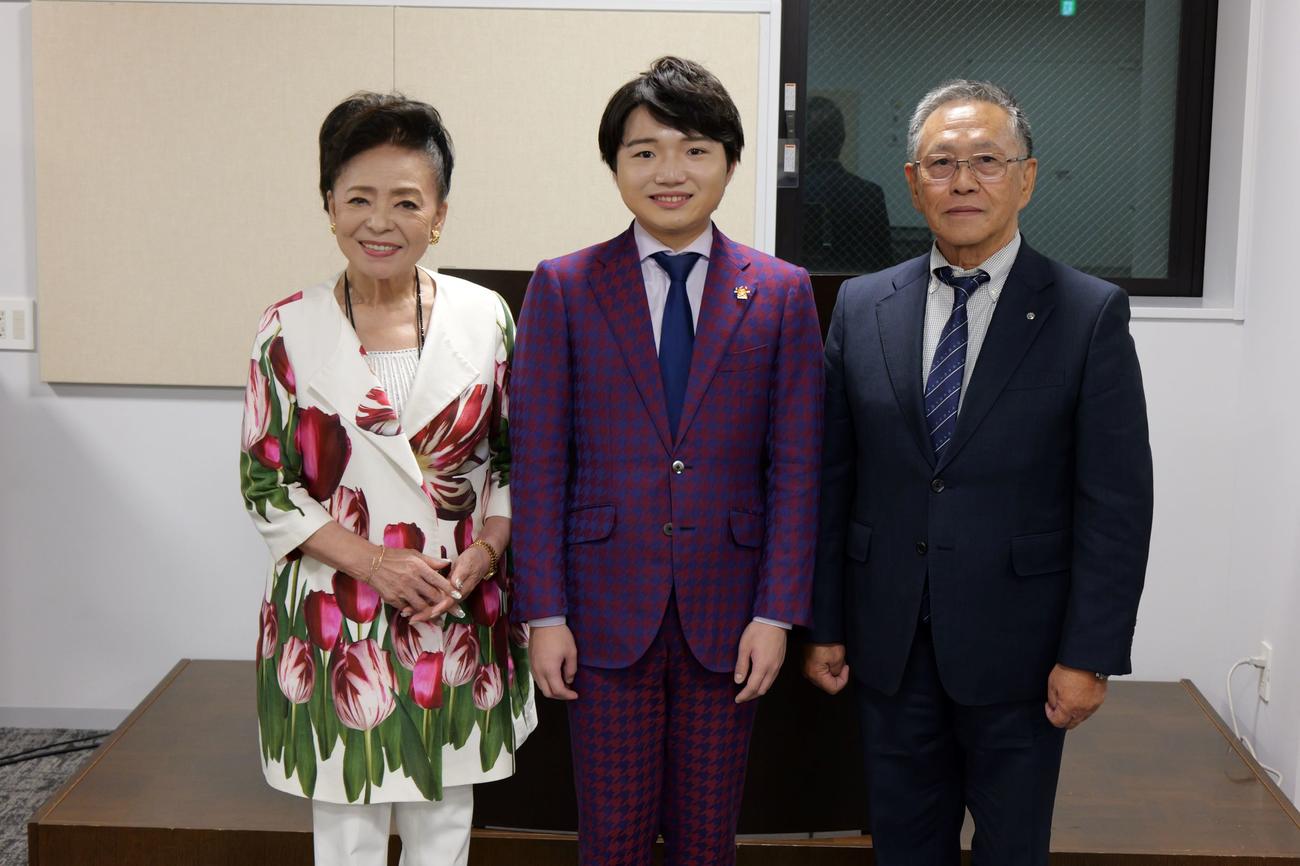 「奥尻島観光大使」の委嘱状を受け取った小山雄大（中央）。左は松前ひろ子、右は奥尻町の新村卓実町長