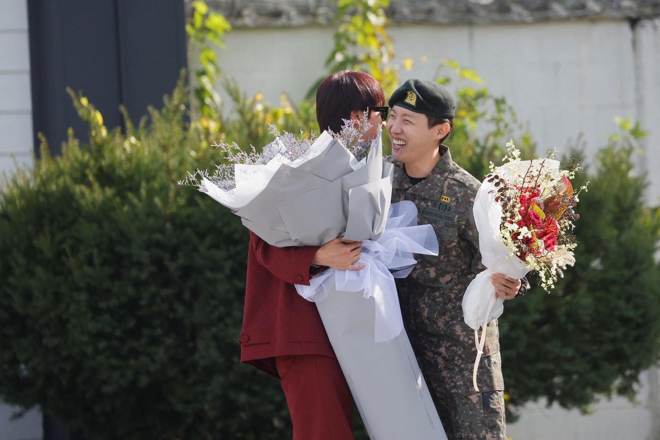 兵役を終えたBTSのJ－HOPE（右）は、先に除隊したJINから花束を受け取る（ロイター）