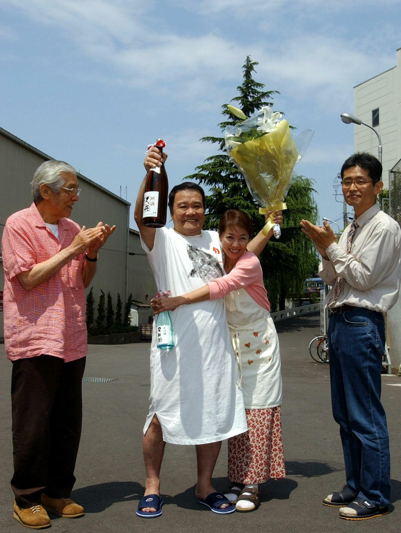 仕事復帰した西田敏行さんは、共演の浅田美代子から花束と日本酒を受け取り笑顔（2003年4月撮影）