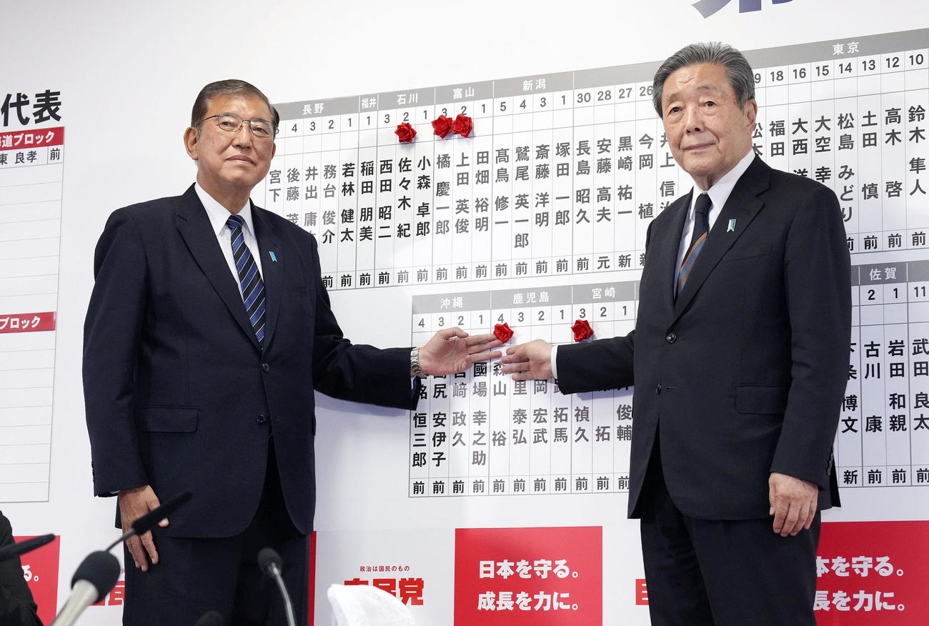 当選を決めた自民党の森山幹事長（右）の名前にバラを付ける総裁の石破首相（共同）