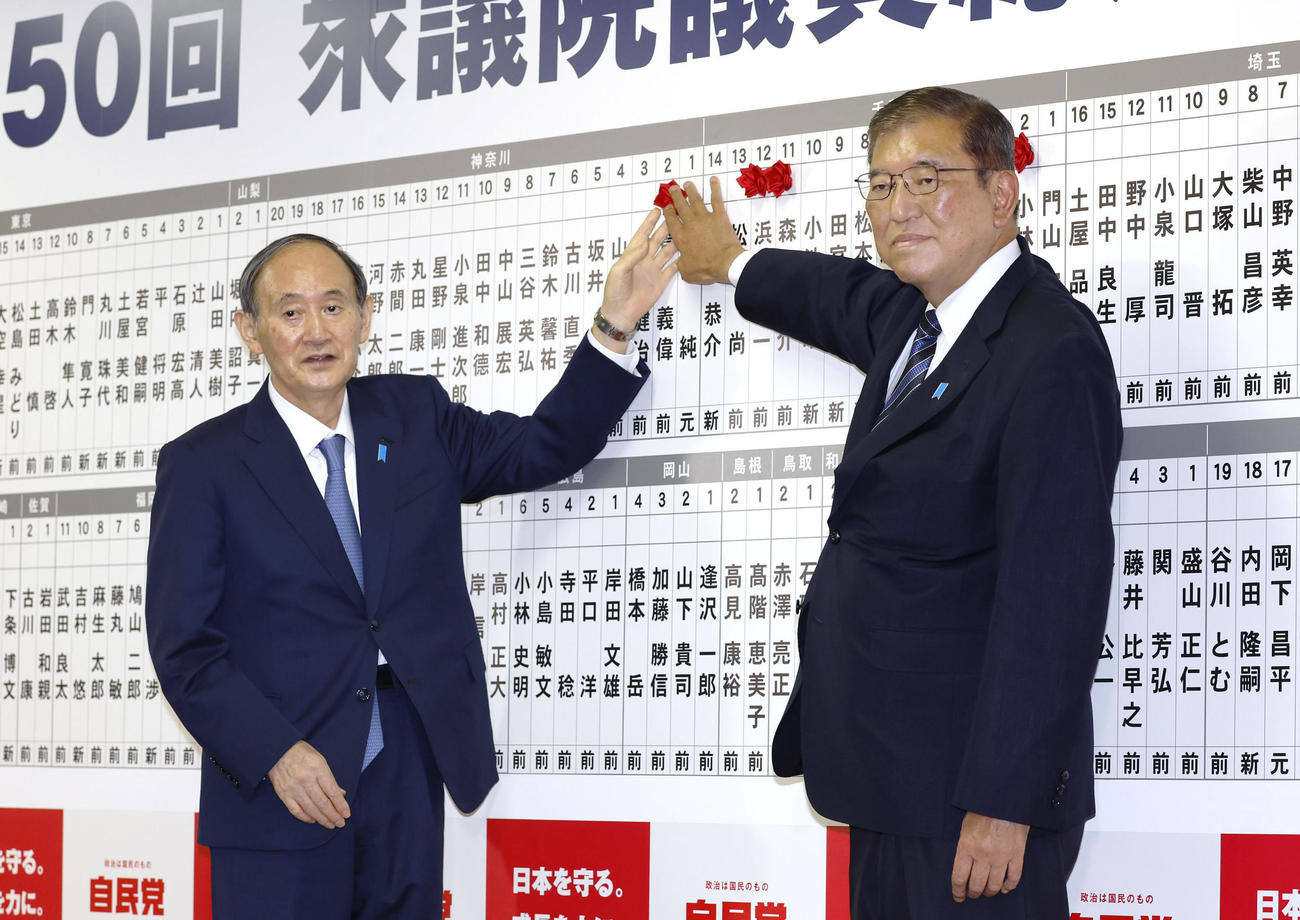 当選を決めた自民党の菅副総裁（左）の名前にバラを付ける総裁の石破首相（共同）
