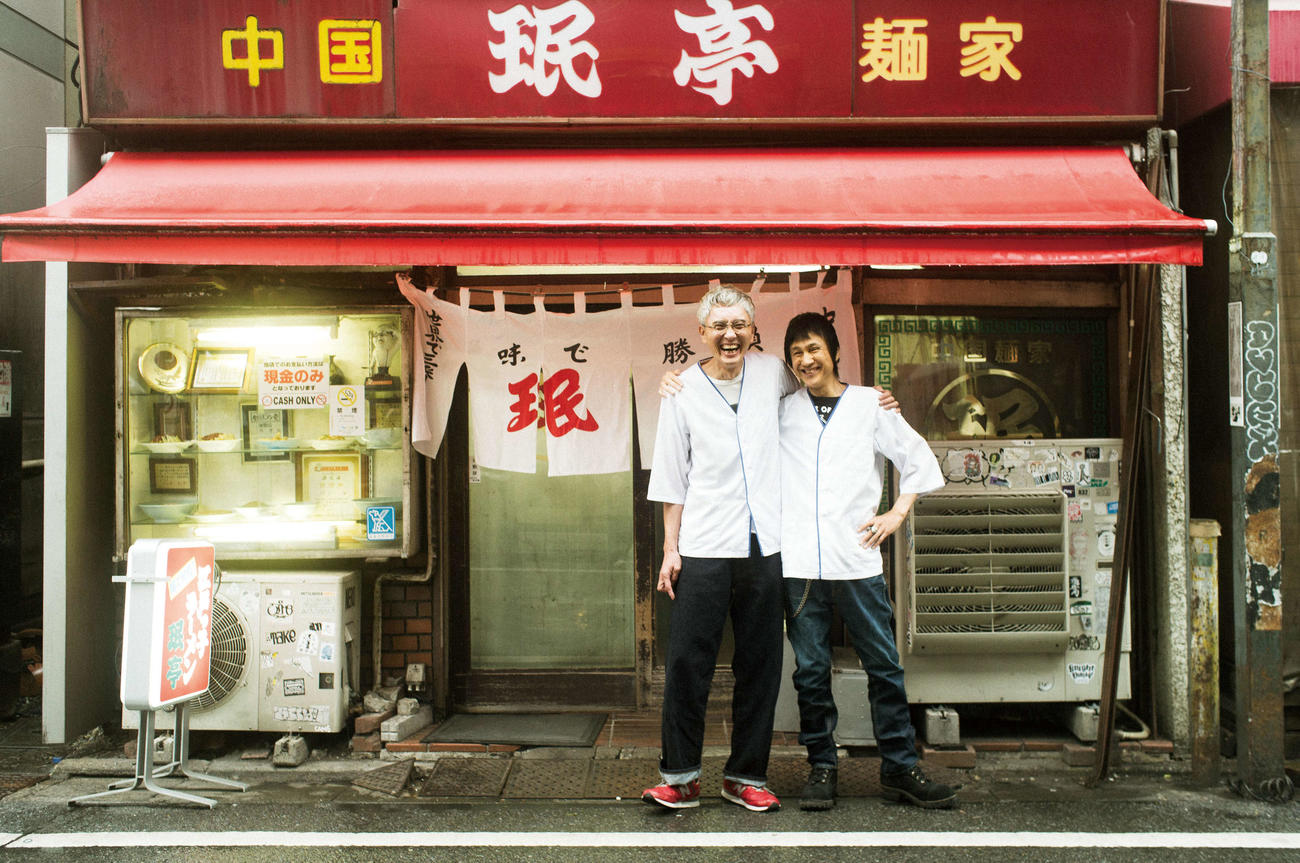 約40年前の同じ日にアルバイトを始めた東京・、下北沢の中華料理屋「珉亭」を前に、当時と同じアルバイ
ト着に袖を通し、記念撮影した松重豊（左）と甲本ヒロト