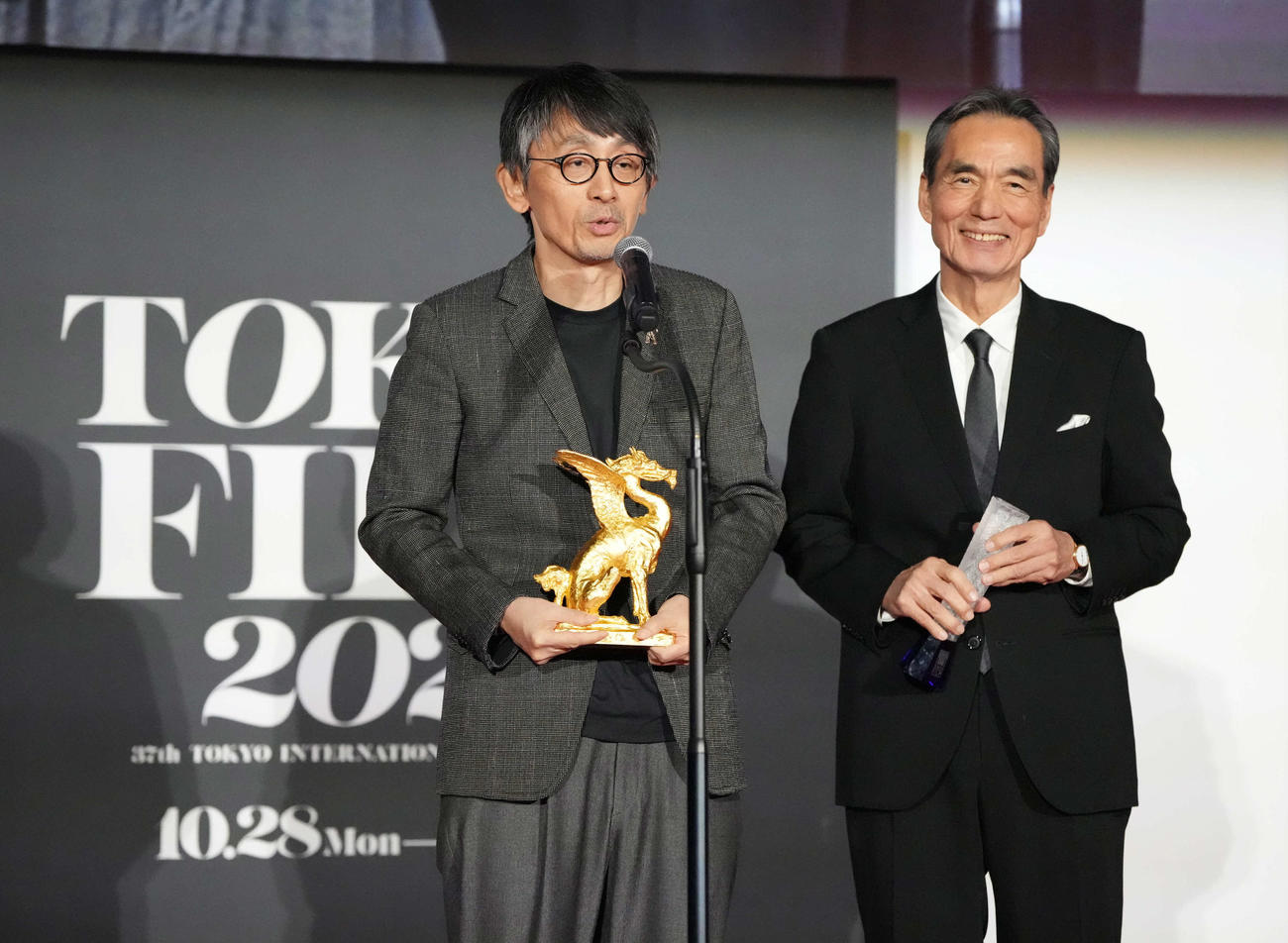 第37回東京国際映画祭「クロージングセレモニー」で映画「敵」がコンペティション部門の東京グランプリ／東京都知事賞を受賞しスピーチする吉田大八監督。右は最優秀男優賞の長塚京三（撮影・小沢裕）